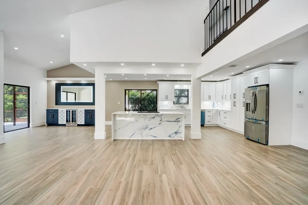 Open-plan living space with wood-look floors and a white kitchen