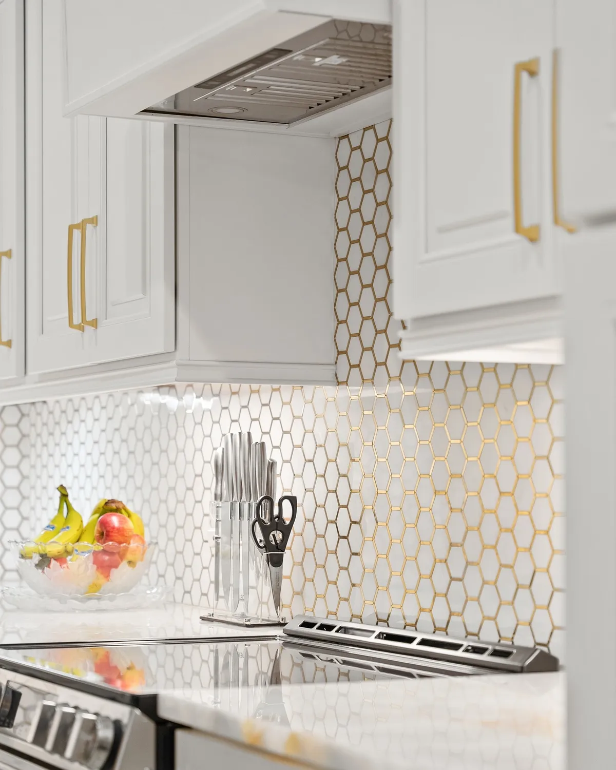 White kitchen cabinets with gold handles and patterned tile backsplash