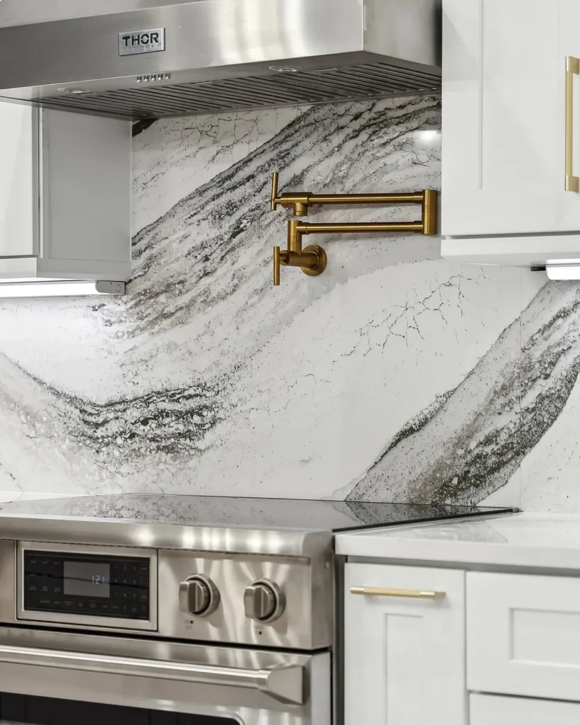 Veined stone backsplash, stainless range and gold pot filler in a remodeled kitchen
