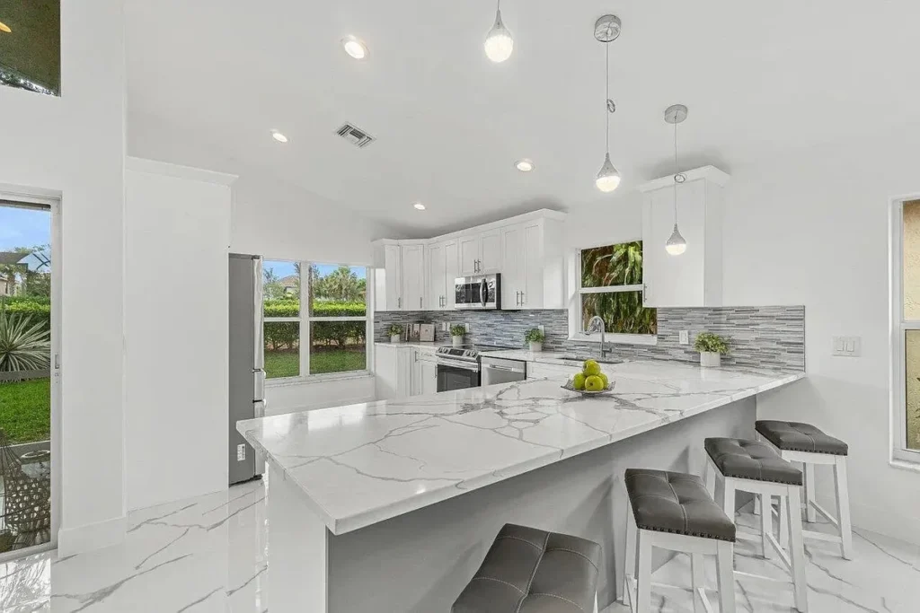 Bright kitchen with a long stone island and upholstered counter stools